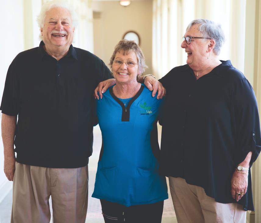 A caregiver stands between the franchise owners at her local office